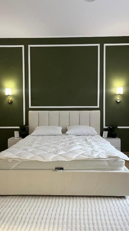 a large white bed in a bedroom with green walls at Studio Yas Central Arad in Arad
