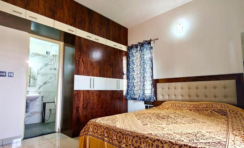 a bedroom with a bed and a window with a curtain at Sheetal Service Apartment in Mangalore