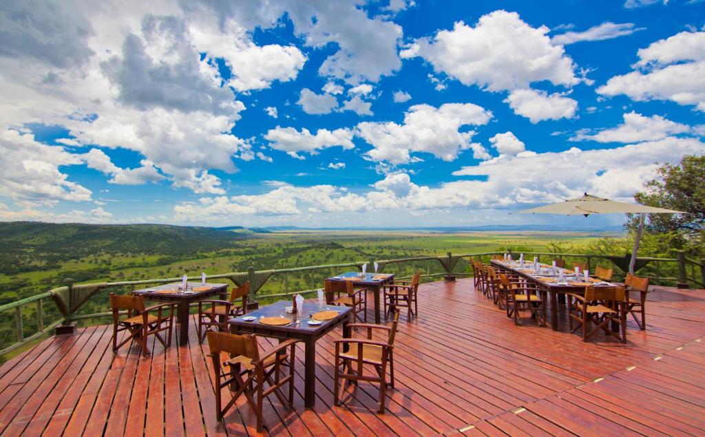 eine Terrasse mit Tischen und Stühlen und Aussicht in der Unterkunft Mbali Mbali Soroi Serengeti Lodge in Banagi