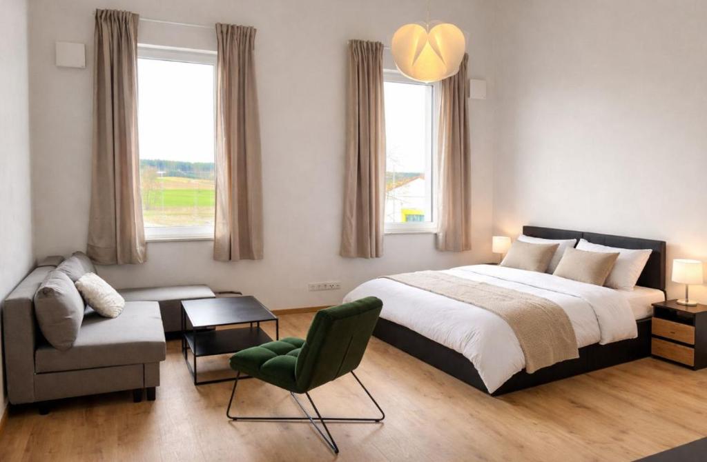 a bedroom with a bed and a chair and a couch at Horgau Living in Horgau