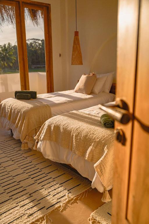two beds sitting next to each other in a bedroom at Green Waves Villa in Batukaras