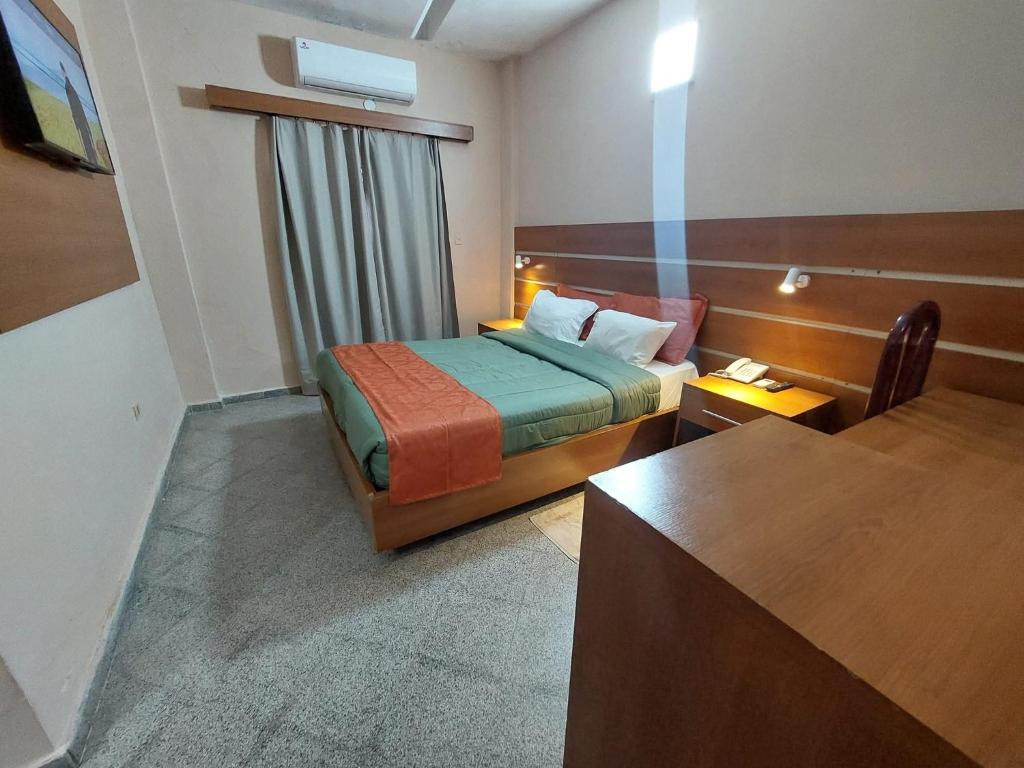 a hotel room with a bed and a desk at Hotel Sancer in Coronel Oviedo