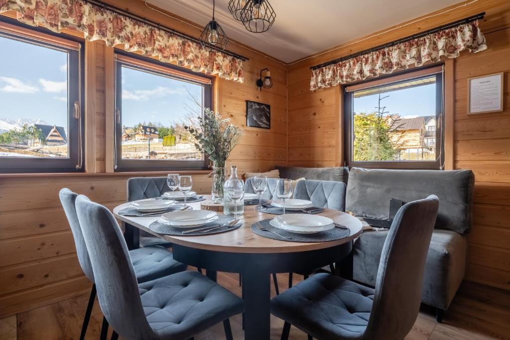 a dining room with a table and chairs and windows at Domek Przy Potoku Murzasichle in Murzasichle