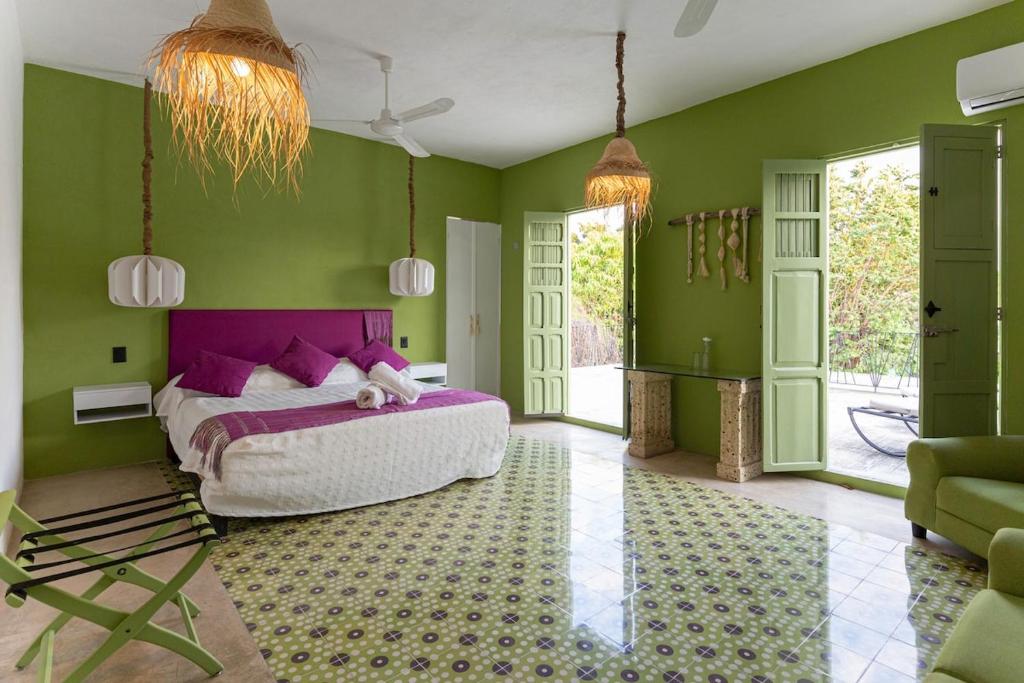 a bedroom with a large bed and green walls at Casa La Gloria, Centro de Mérida, Hasta 16 Huéspedes in Mérida