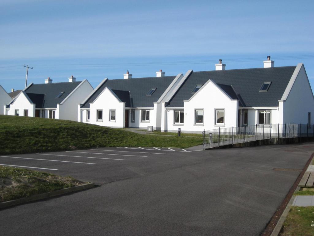eine Reihe von weißen Häusern mit schwarzen Dächern in der Unterkunft 30 Dun an Oir in Ballyferriter