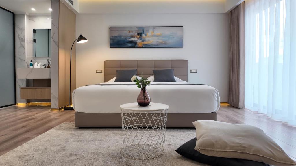 a bedroom with a large bed with a vase on a table at CCLUX Suites - Premium 40sqm Suites near Piraeus Port in Piraeus