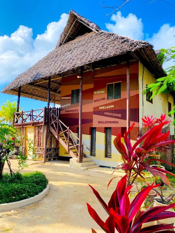 a house with a thatched roof with a staircase at Basecamp Changani in Dar es Salaam