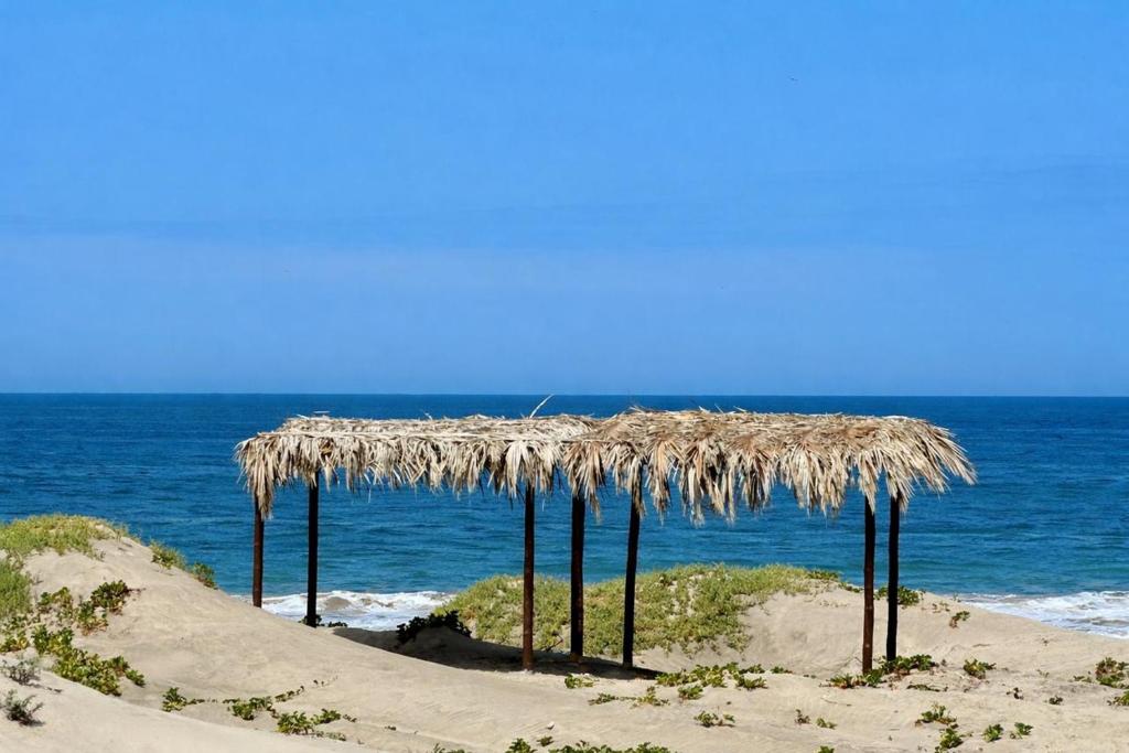 a straw umbrella on a beach near the ocean at Villa Vichayo Bungalows in San Martín
