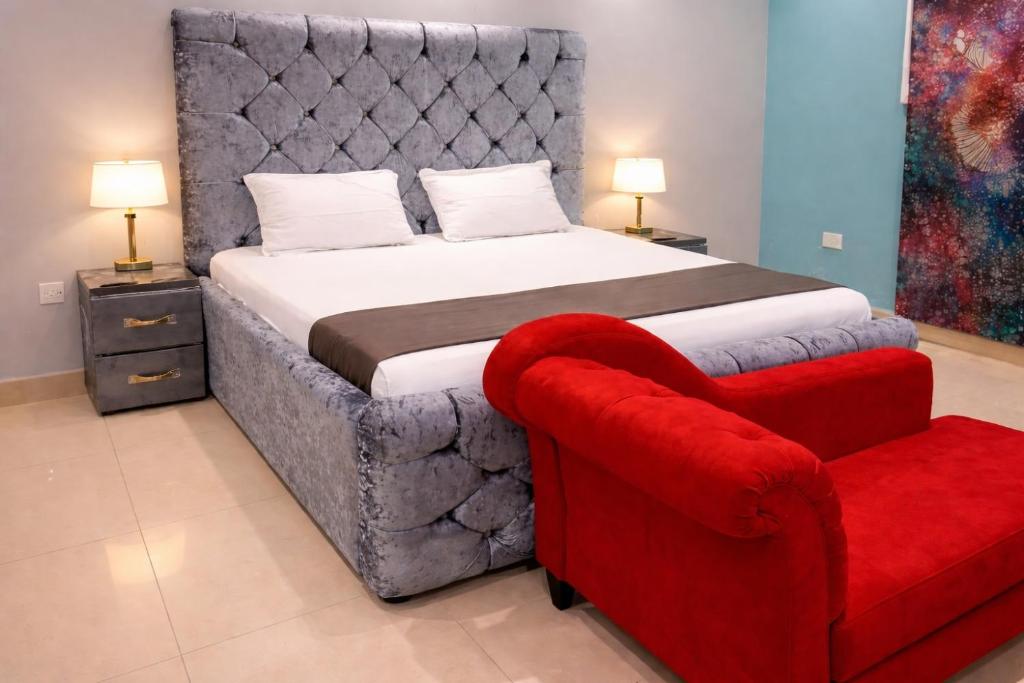 a bedroom with a large bed and a red chair at Cutting Edge Guest House in Daranka