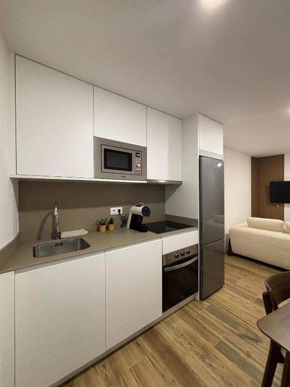 a kitchen with white cabinets and a stainless steel refrigerator at Coração d`Alice in Monção