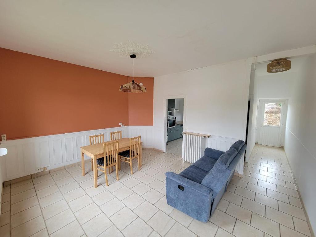 a living room with a blue couch and a table at Maison proche gare in Margny-lès-Compiègne