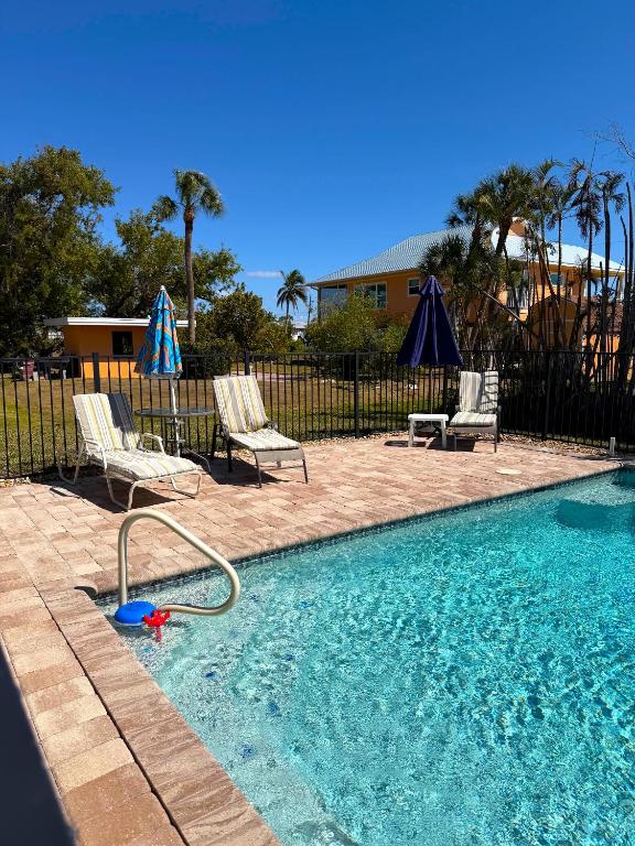 a swimming pool with two chairs and a hose in the water at Driftwood Getaway Vacation home in Fort Myers Beach