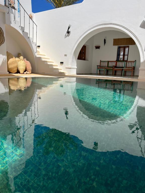 a swimming pool with blue water in a building at Houch Ennejma in Al Ḩārah al Kabīrah