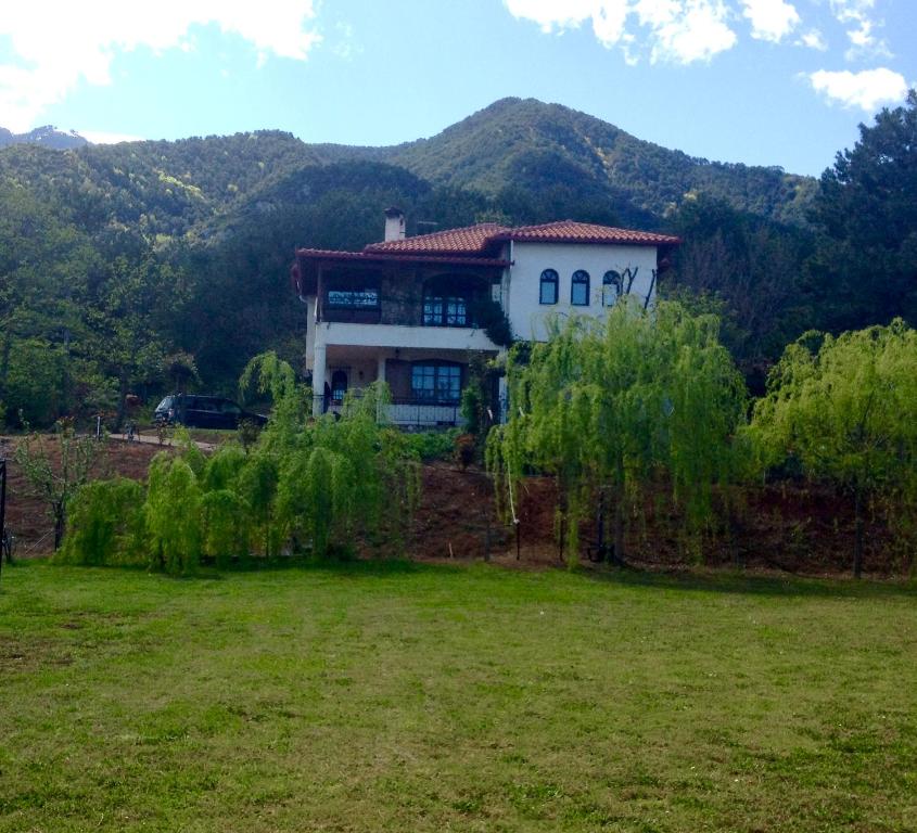 a house on top of a field with mountains in the background at Koti Mountain House in Litochoro