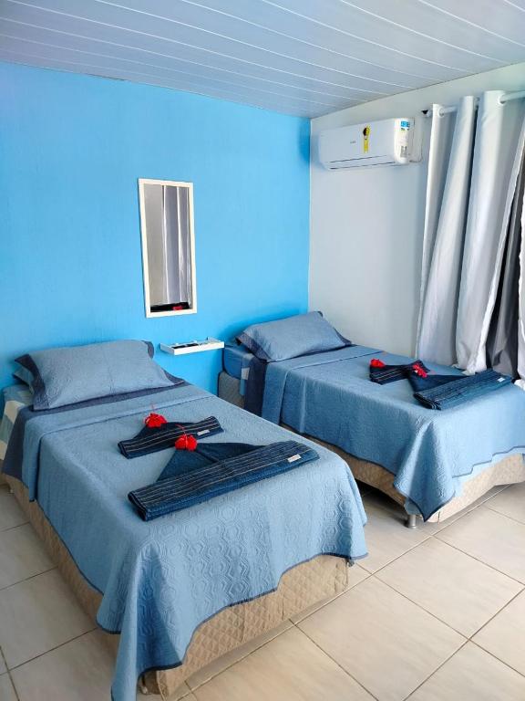 two beds in a blue room with red roses on them at Casa Noronha tropical 2 in Fernando de Noronha