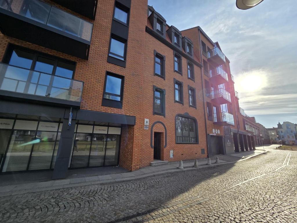 a red brick building on a cobblestone street at JustInRent Family Szpitalna 4D-3 in Legnica