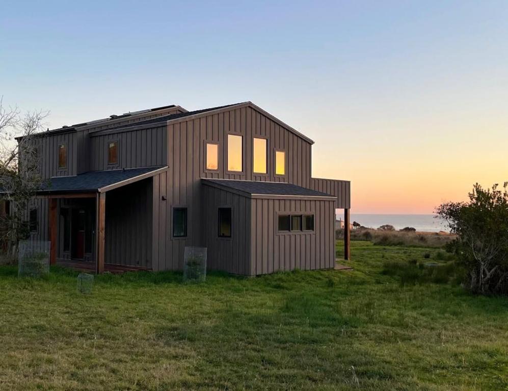 a house in a field with the ocean in the background at Coastal Calm at Sea Ranch in Sea Ranch