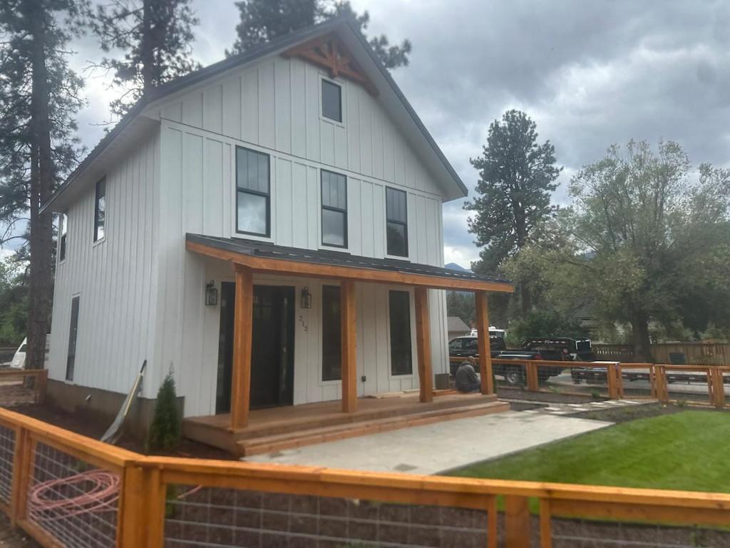a white house with a porch and a fence at The Farmhouse in Darby