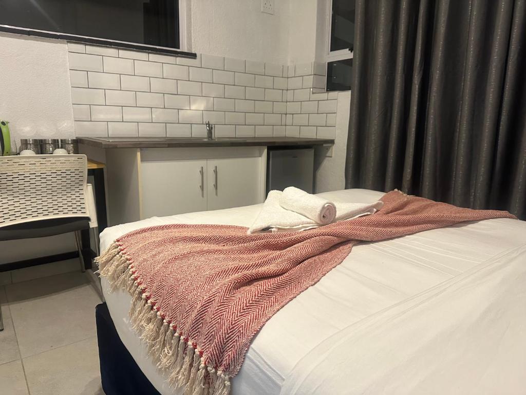 a bed with a blanket on it in a room at Bell rose oaks guest house in Blomtuin