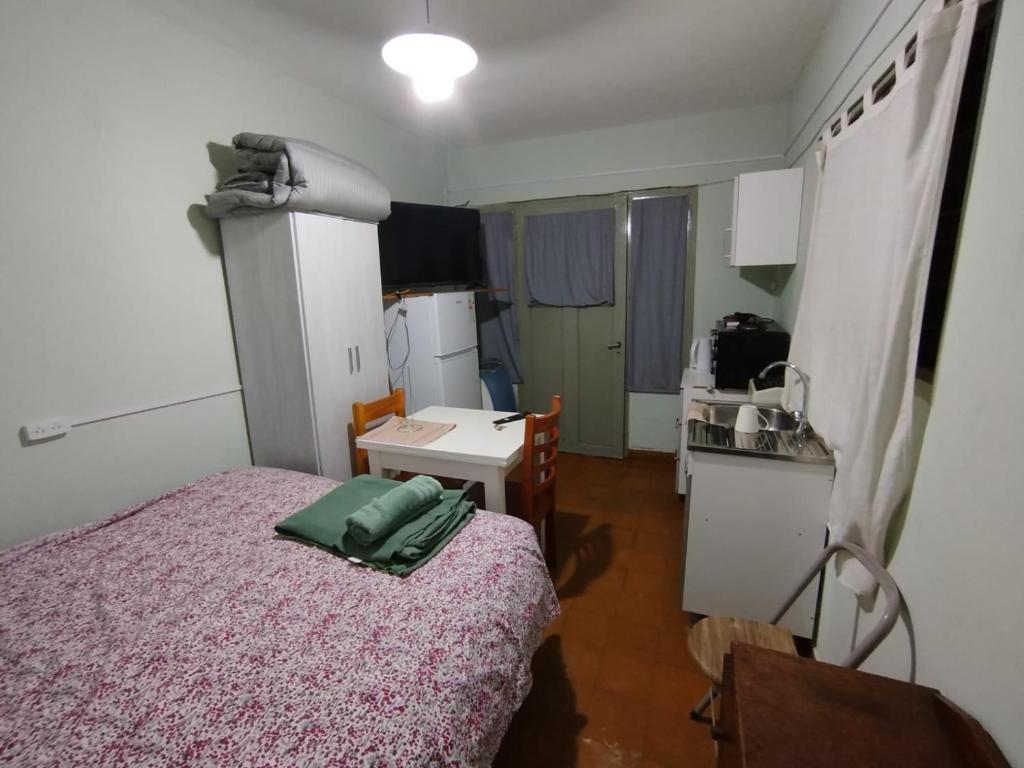 a bedroom with a bed and a table and a kitchen at Jujuy 555 Nqn in Neuquén