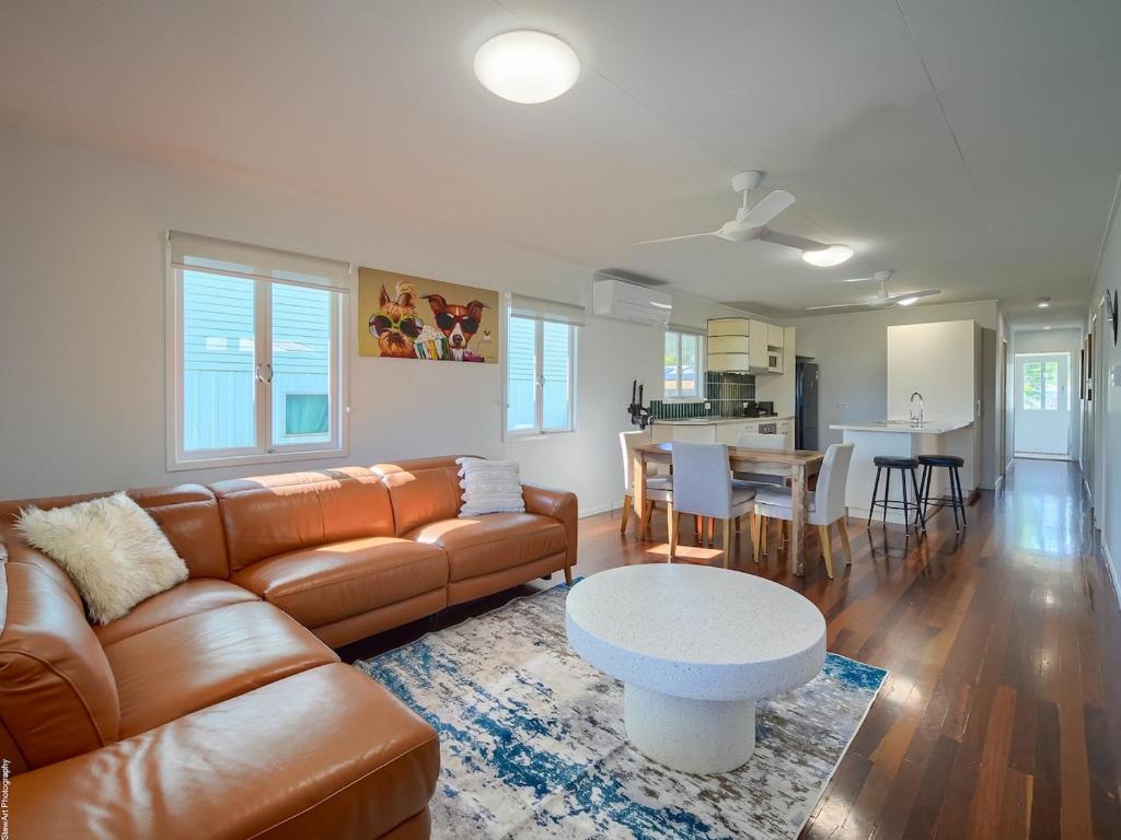 a living room with a leather couch and a table at Ocean Getaway in Hervey Bay