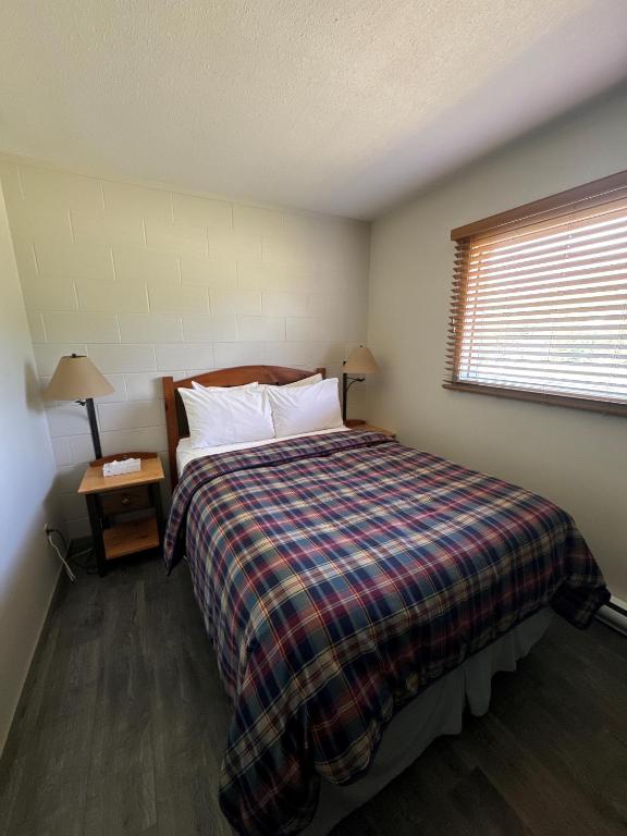 a bedroom with a bed with a plaid blanket and a window at Saddle Mountain Lodge in Blue River