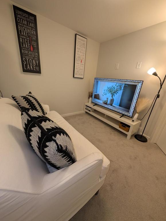 a living room with a white couch and a flat screen tv at Modern Private Suite - Quiet & Central Winnipeg in Winnipeg