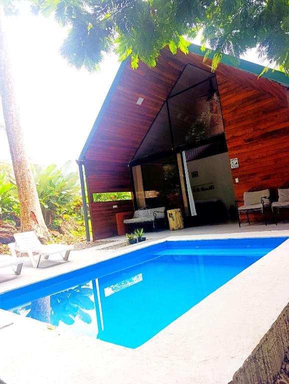a house with a swimming pool in front of it at Cabaña Kono Rainbow Finca paraíso in Jiménez