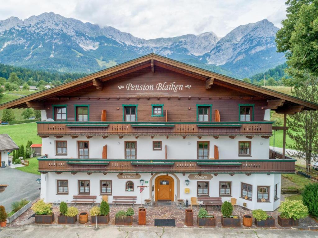 a large building with mountains in the background at Pension Blaiken M in Scheffau am Wilden Kaiser