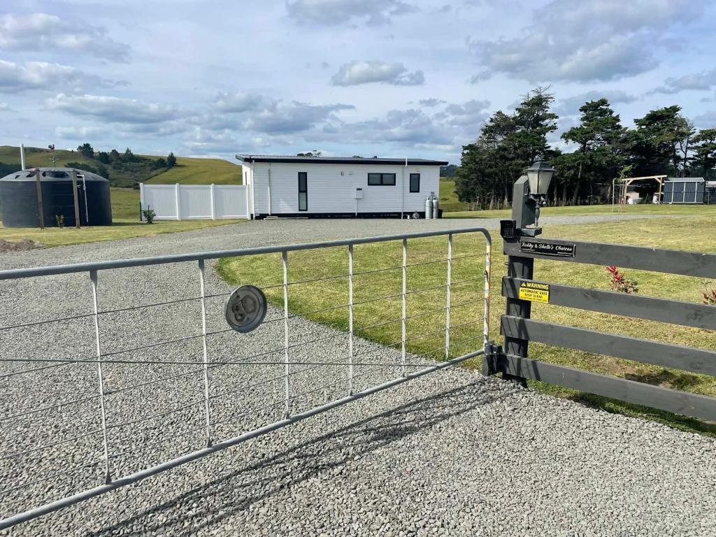 a fence in front of a building with a house at Boutique Tiny House Stargazing & Rural Views in Parore