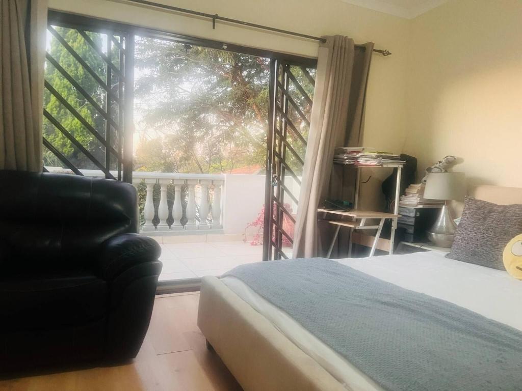 a bedroom with a bed and a view of a balcony at 3 bed Cluster home in Sandton in Sandton