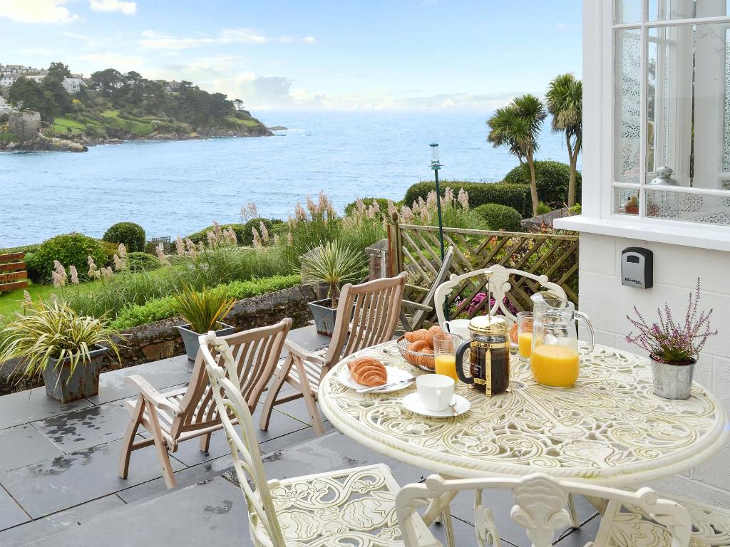 a table with breakfast on a balcony with a view of the ocean at Tides Reach in Fowey