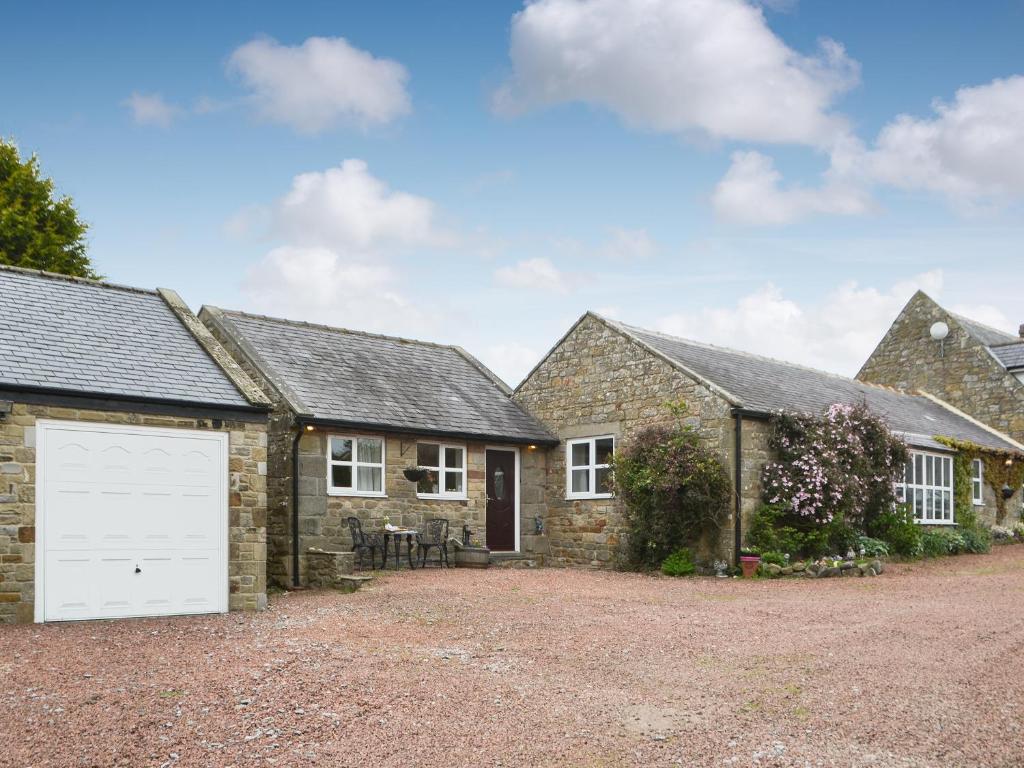an old stone house with a white garage at The Gin Gan Cottage in Ryal