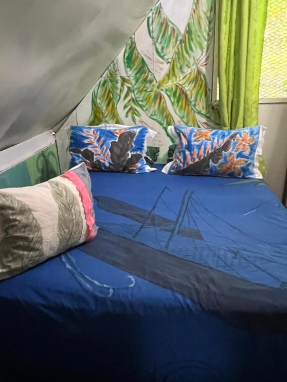 a bed in a tent with blue sheets and pillows at Chalet Avapeihi in Fitii