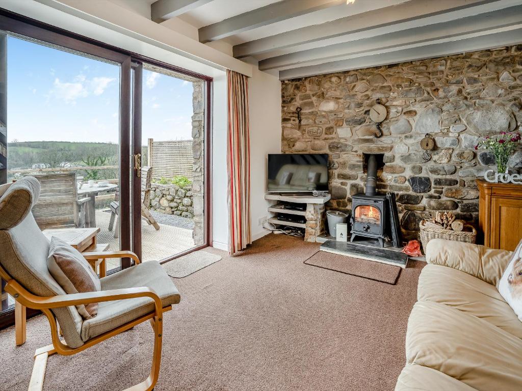 a living room with a fireplace and a stone wall at Granary Cottage - Uk10695 in Amroth
