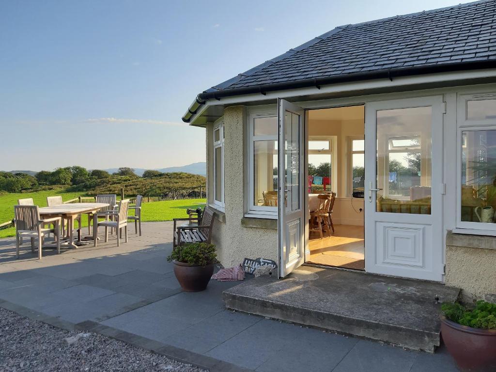 a house with a glass door and a patio at Degnish Farmhouse - Swwu in Kilmelfort