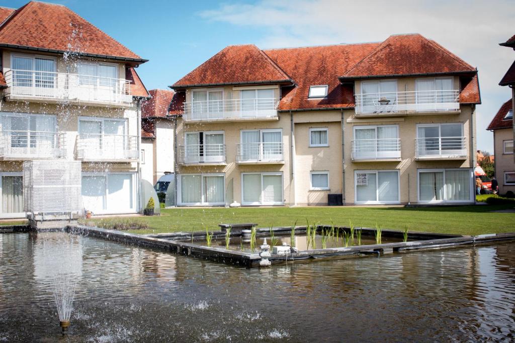 a large apartment building next to a body of water at Holiday Suites De Haan in De Haan