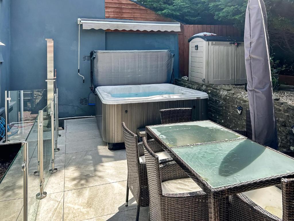 a patio with a table and a bath tub at Honeycott in Crickhowell