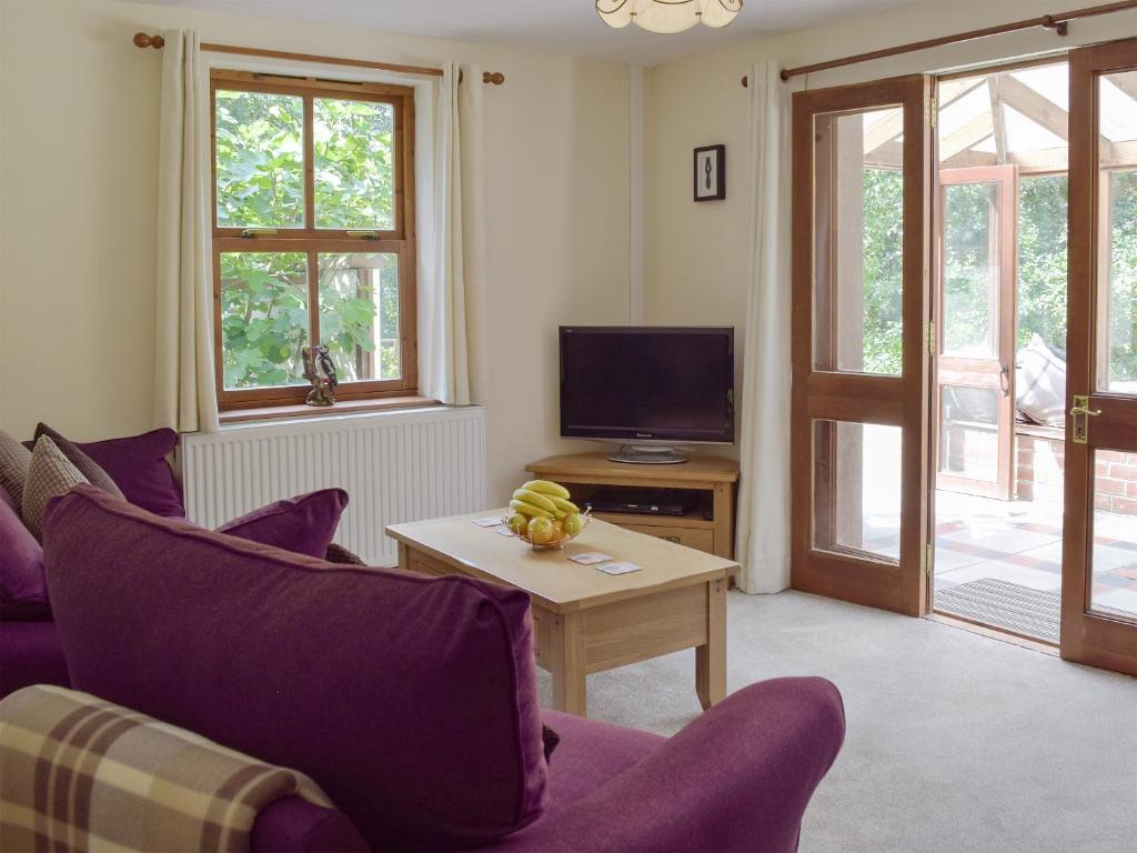 a living room with purple furniture and a tv at Woodpecker Rest in Cilgerran