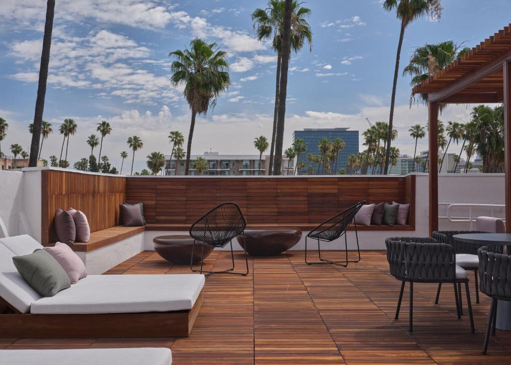 a rooftop patio with chairs and tables and palm trees at The Ivory in Los Angeles