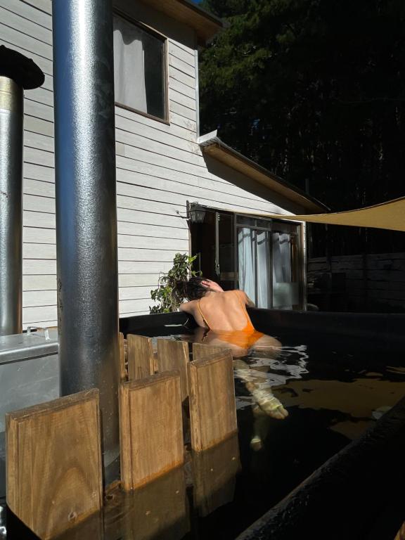 a man is in the water next to a house at Cabaña en Buchupureo in Tiuquilemu