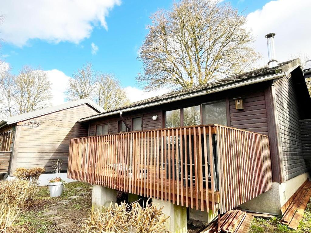a house with a wooden deck on the side of it at Cozy chalet for 6 people in Rendeux