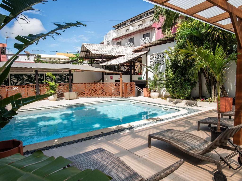 a swimming pool with two chairs next to a building at Ibis Styles Cayenne Centre Amazonia in Cayenne
