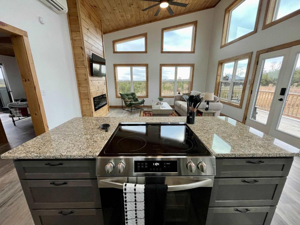 a kitchen with a stove and a living room with windows at Spruce Arch - King Bed Fireplace Pets Welcome in Rogers