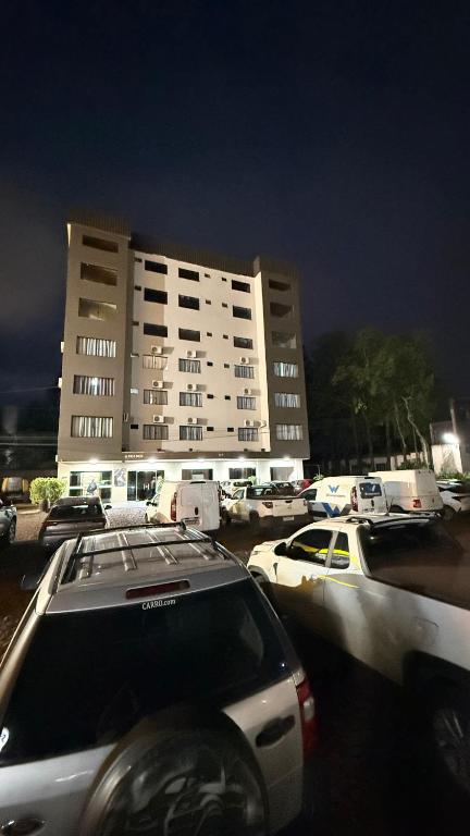 a parking lot with cars parked in front of a large building at Hotel Guia lopes in Santa Rosa