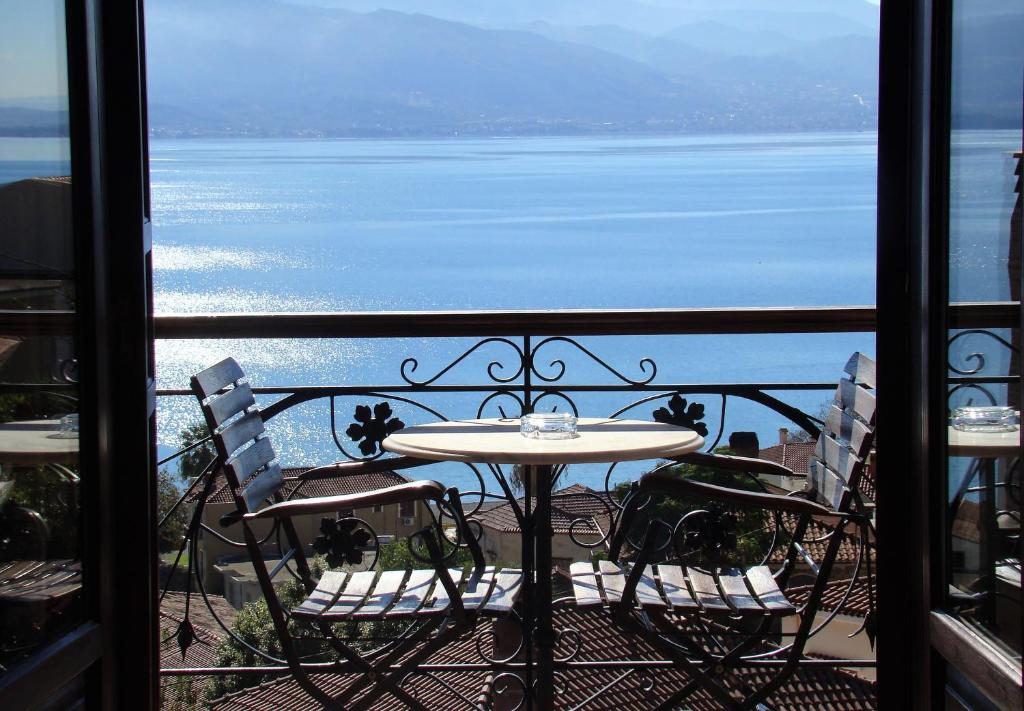 einen Tisch und Stühle auf einem Balkon mit Blick auf das Wasser in der Unterkunft Ilion Hotel in Nafpaktos