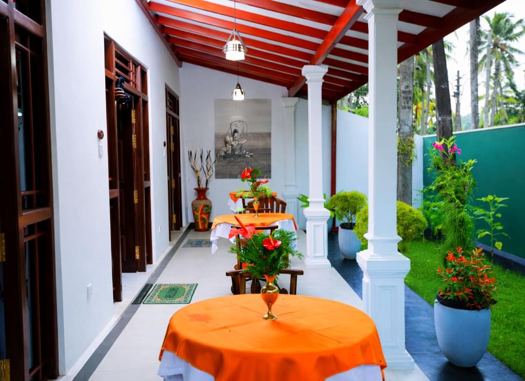 a porch with two tables and flowers on it at Ceylonika Rest in Bentota