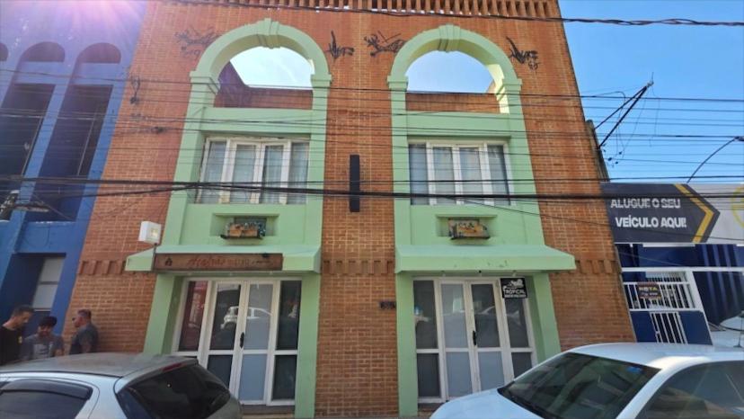 a brick building with arched windows and cars parked in front at Horizon 2 andar in Marataizes