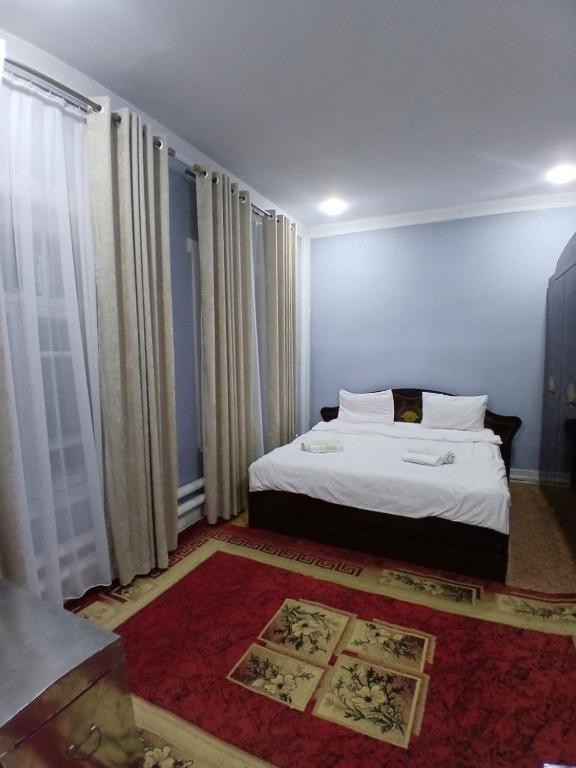 a bedroom with a white bed and a red rug at Uyut house in Samarkand