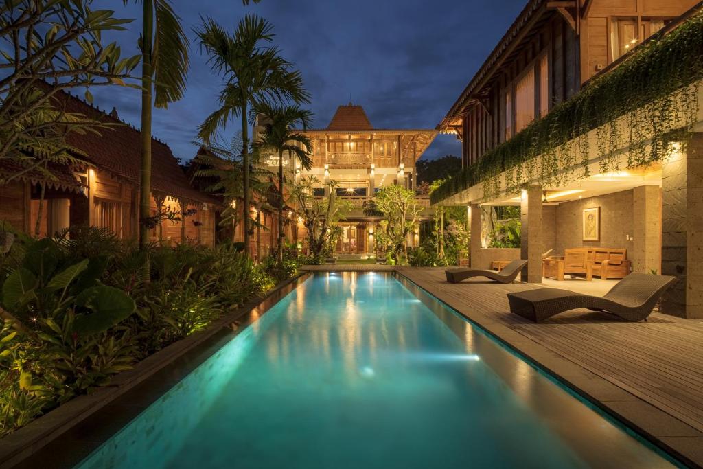 a swimming pool in front of a building with a house at Jero Jawi Javanese Villa in Lebih